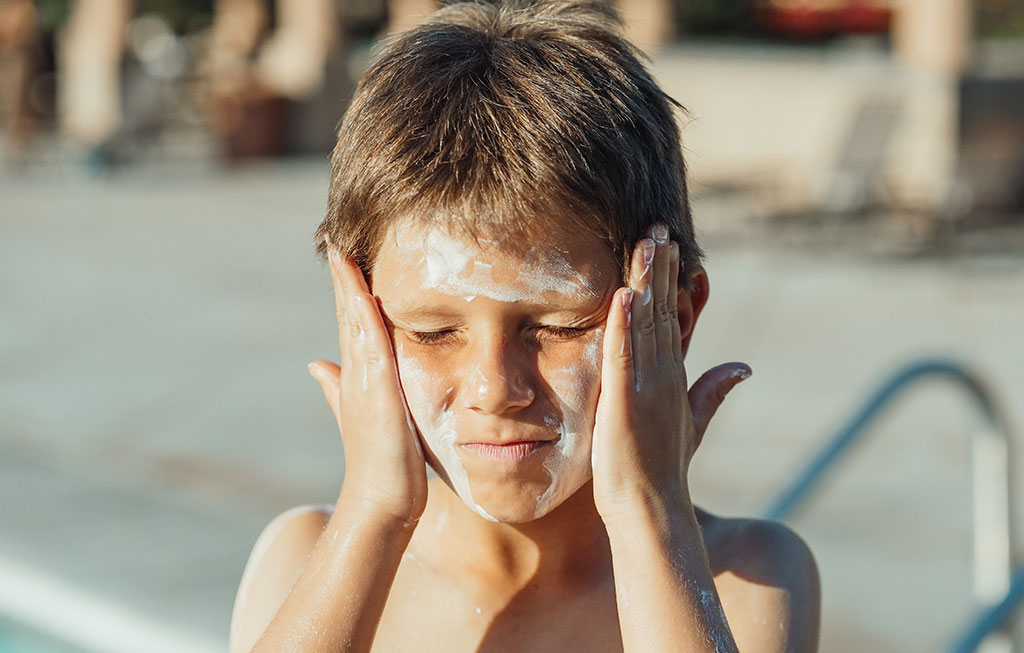 un niño se echa protector solar en la cara