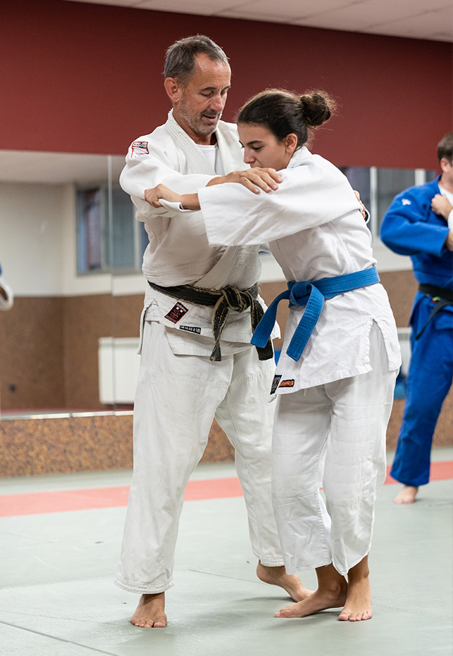 profesor ayuda a joven aprendiendo judo
