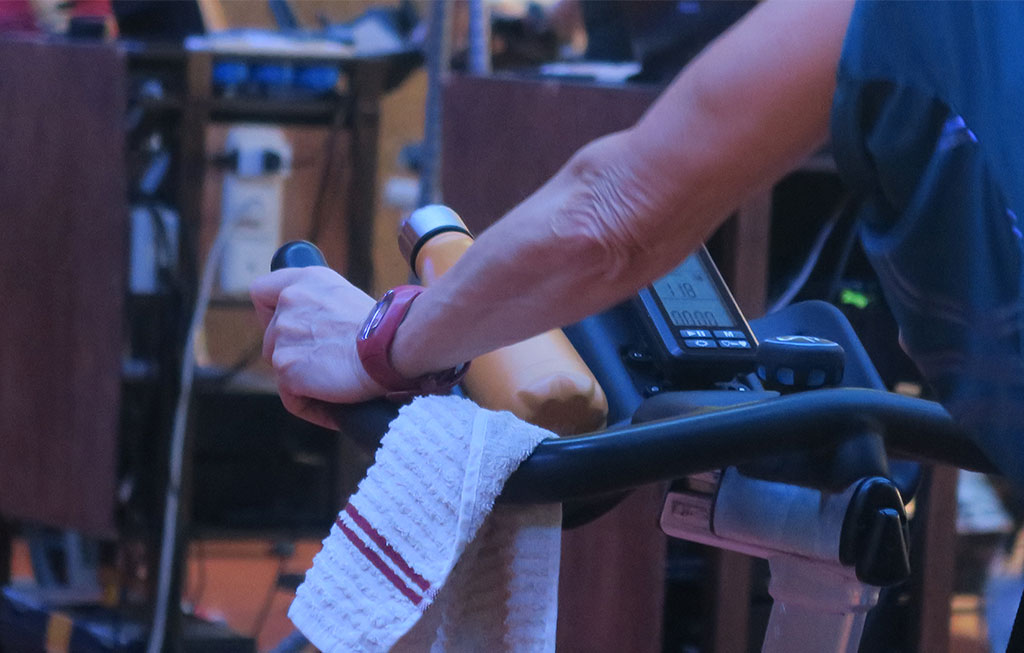 brazos de una mujer que está haciendo ejercicio en la bicicleta estática en el gimnasio