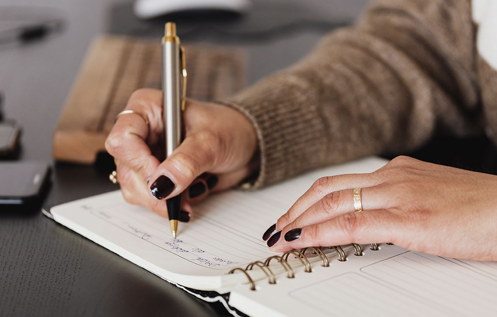 manos de mujer escribiendo en una agenda sus objetivos