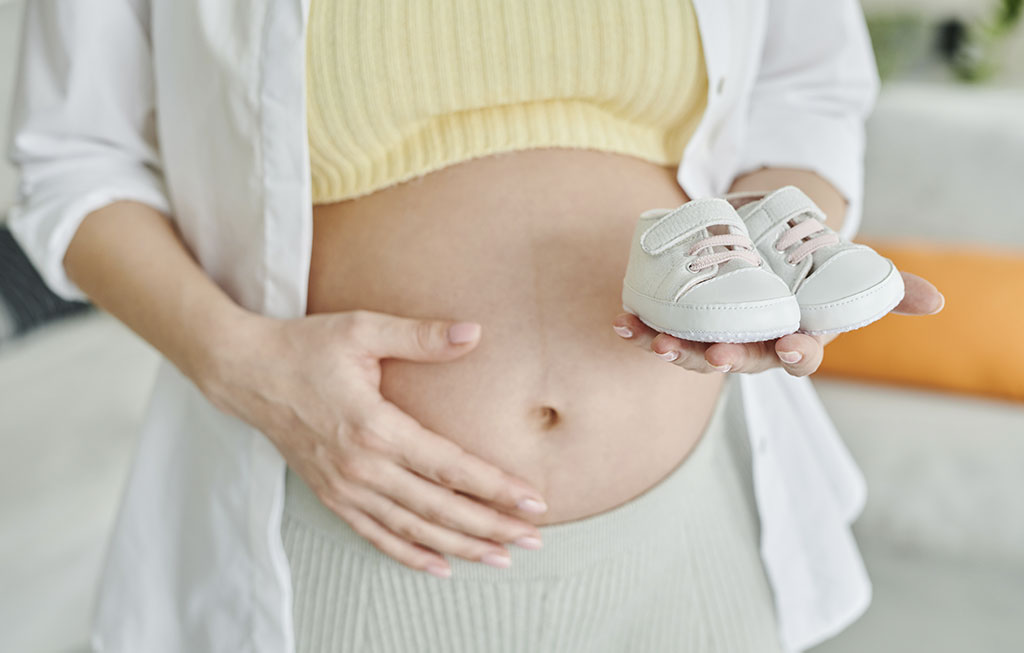 mujer embarazada con unas zapatillas deportivas de bebé en la mano