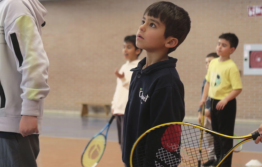un alumno con una raqueta mira hacia la pelota