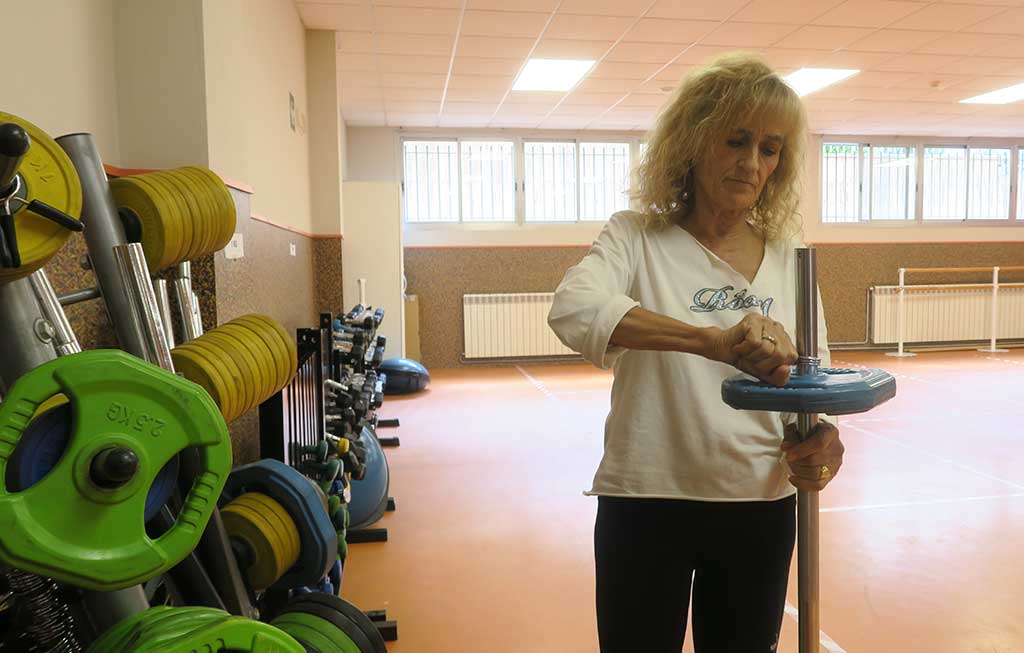 una mujer deportista prepara una pesa para la clase de tonificación del gimnasio