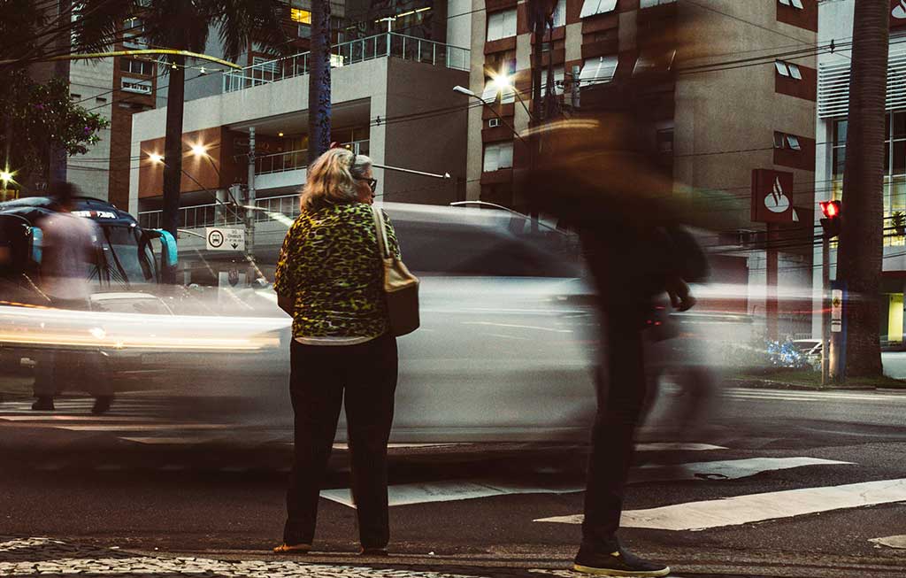 Una mujer en la calle mira a un coche que pasa rápidamente 