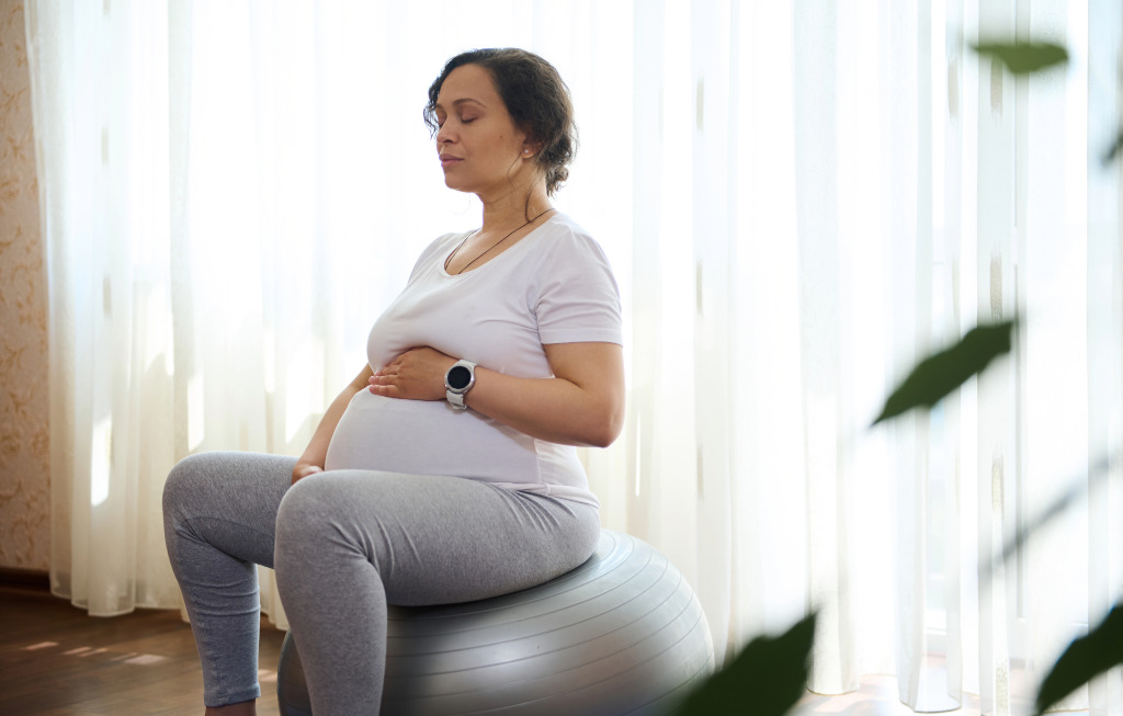 una mujer embarazada sentada sobre un balón de fitness