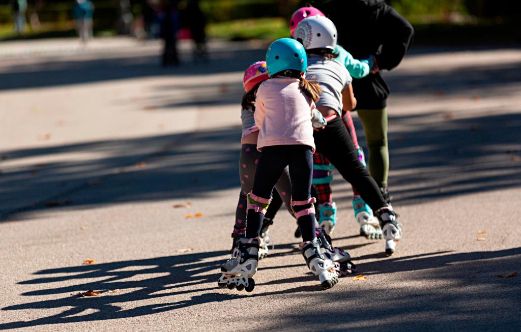 varios niños patinan uno detrás de otro
