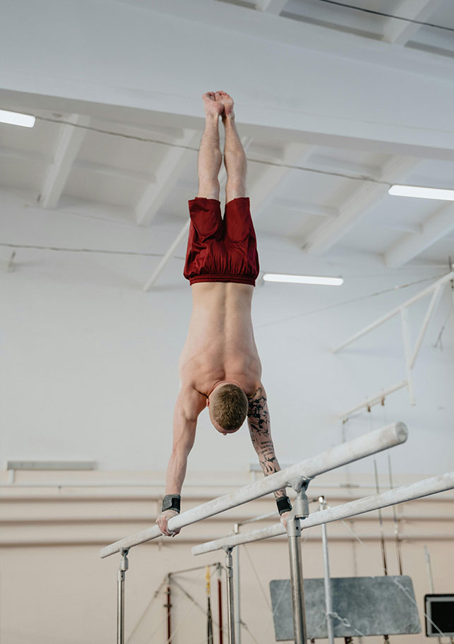 gimnasta masculino hace el pino sobre las barras paralelas