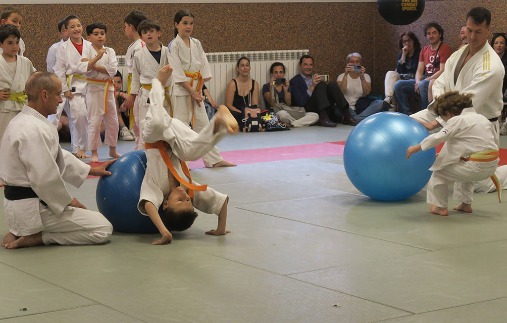 judokas haciendo volteretas sobre pelotas de yoga ayudados por un profesor