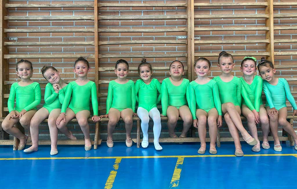 gimnastas infantiles sentadas en fila en el gimnasio