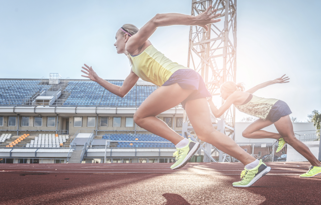 mujeres corriendo en la línea de salida de una pista de atletismo