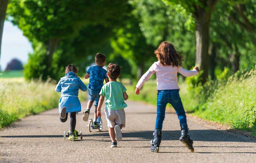 niños patinando en un camino rodeado de vegetación