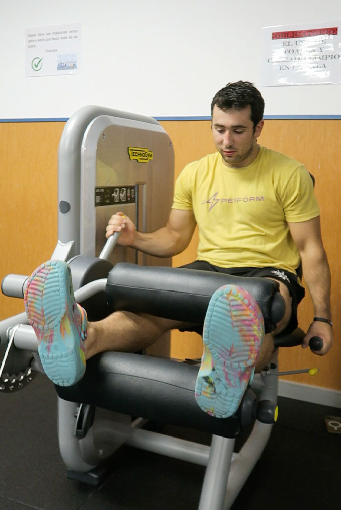 hombre utiliza la máquina leg curl en el gimnasio