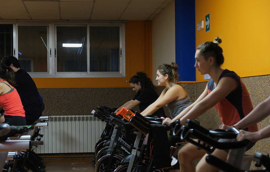 Clase dirigida de CicloFit. Jóvenes sobre bicicleta estática de spinning.