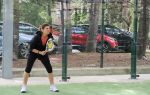 una mujer con una pala de pádel en la mano en posición para jugar a pádel en una pista en Pamplona