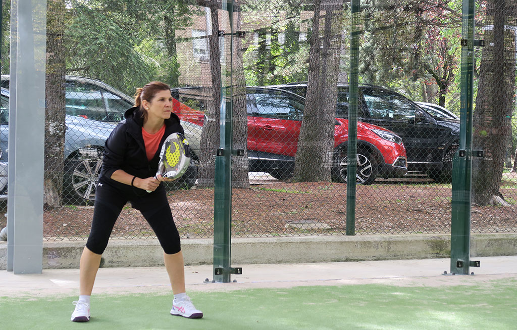 una mujer con una pala de pádel en la mano en posición para jugar a pádel en una pista en Pamplona