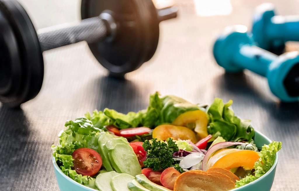 Ensalada rica en nutrientes, con una mancuerna detrás que demuestra el balance.